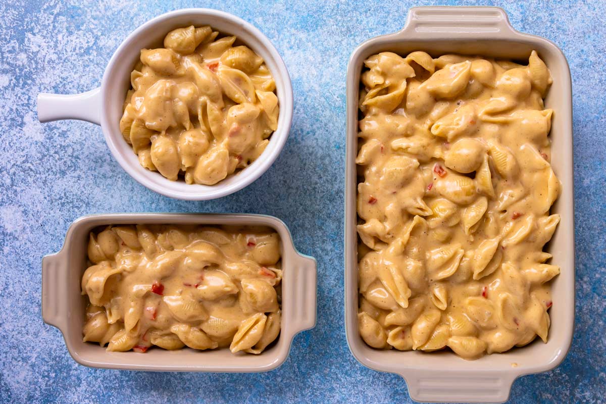 Cajun mac and cheese divided into three baking dishes of varying sizes.
