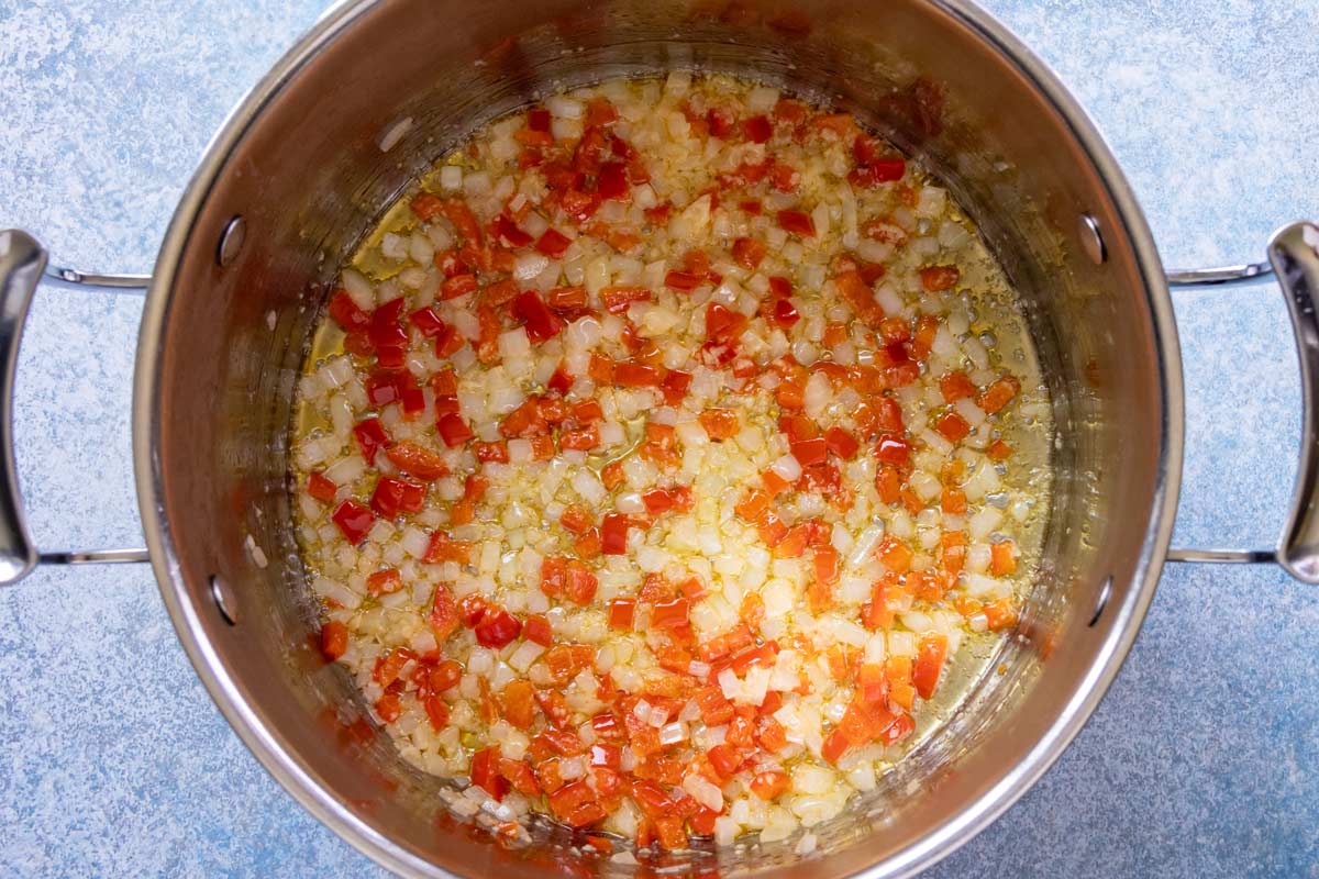 Minced garlic added to a pot of sauteed onion and red pepper.