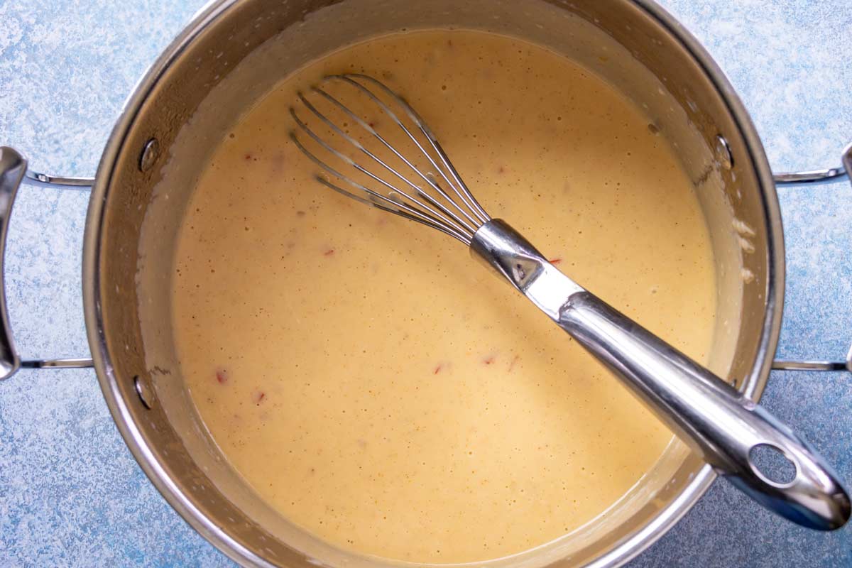 A pot of thick and luscious cheese sauce for making Cajun macaroni and cheese.