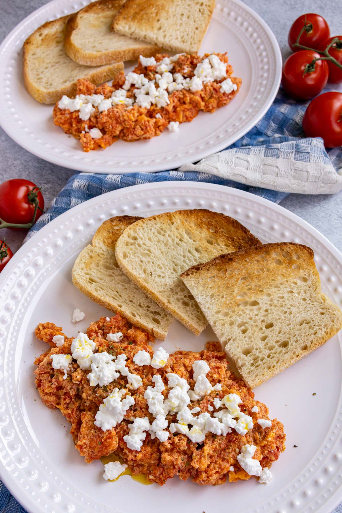 Two plates of Greek strapatsada scrambled eggs with tomatoes served with toast.