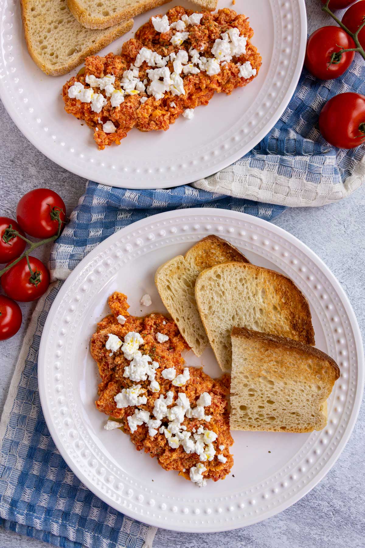 Greek scrambled eggs with tomatoes served with toast on a white plates.