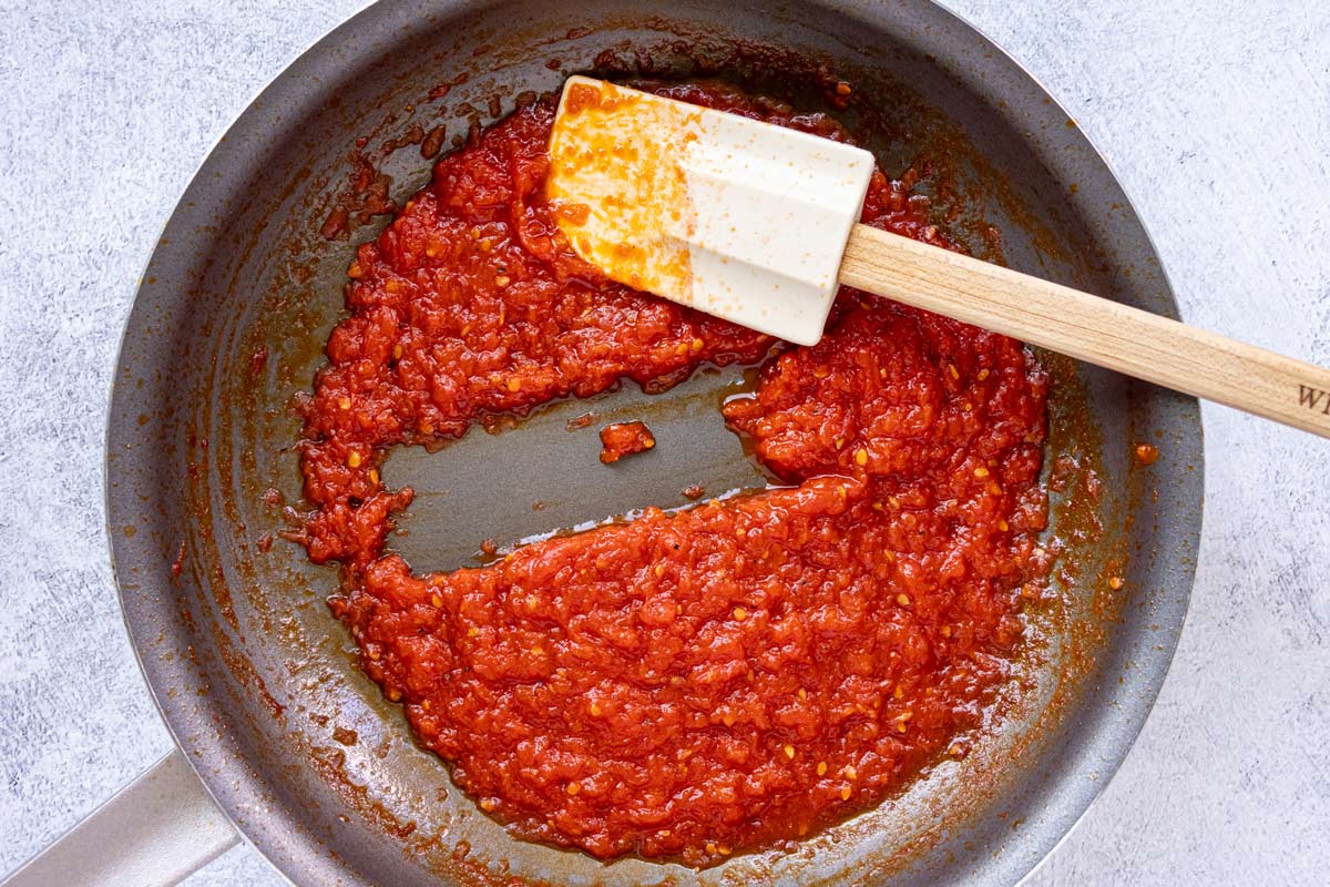 A rubber spatula swiped through a thick tomato mixture in a nonstick skillet.