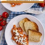 Greek scrambled eggs with tomatoes served with toast on a white plates.