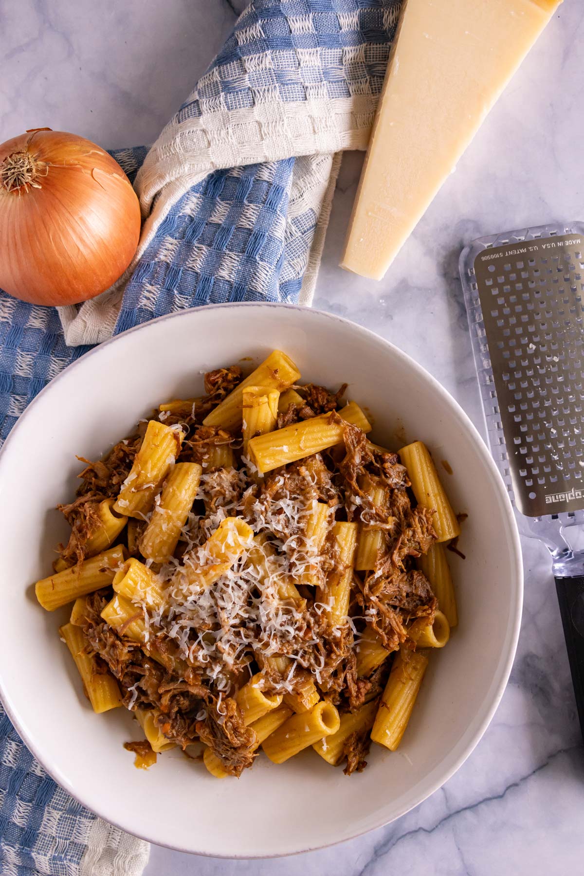 A bowl of Pasta alla Genovese on top of a blue gingham kitchen towel.