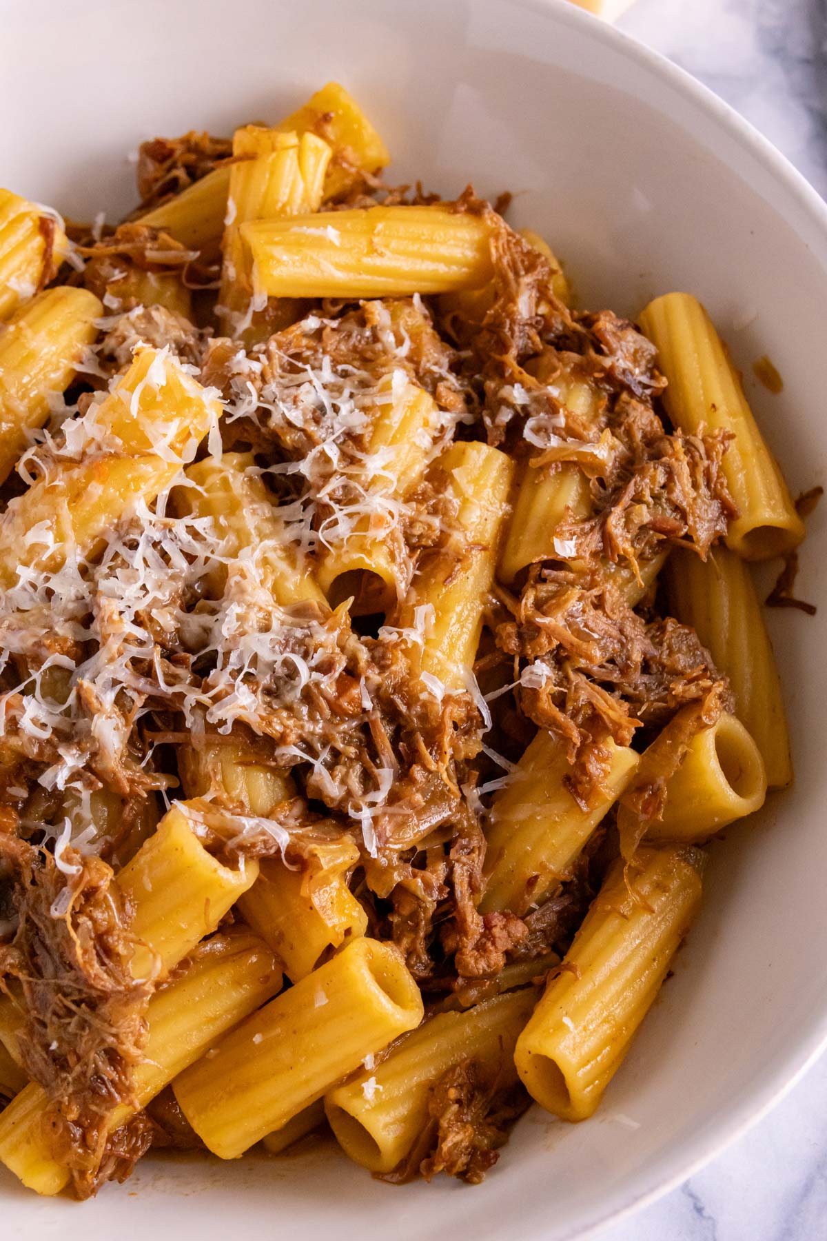A bowl of Pasta alla Genovese with freshly grated Parmigiano-Reggiano on top.