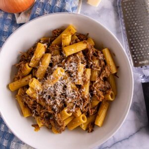 A bowl of Pasta alla Genovese on top of a blue gingham kitchen towel.