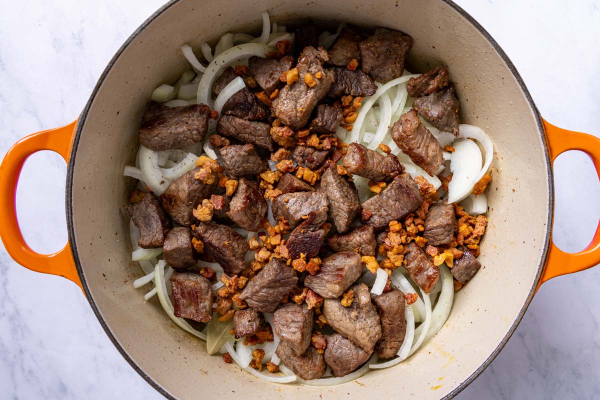 Seared cubed beef and pancetta added to a Dutch oven.