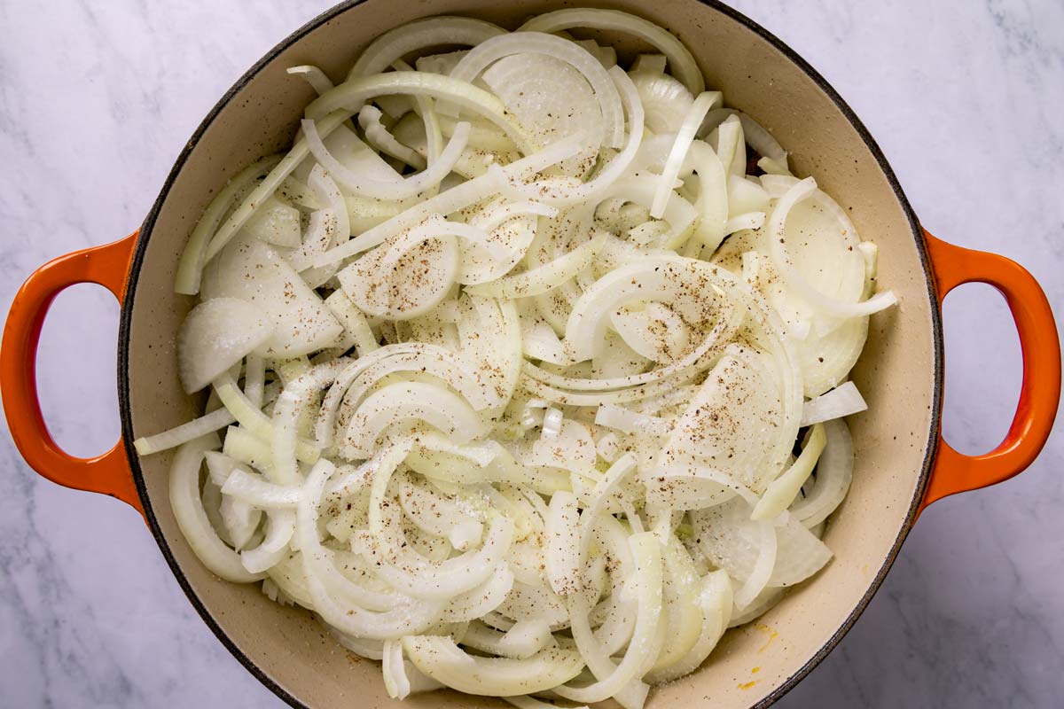 More sliced onions added to a Dutch oven.