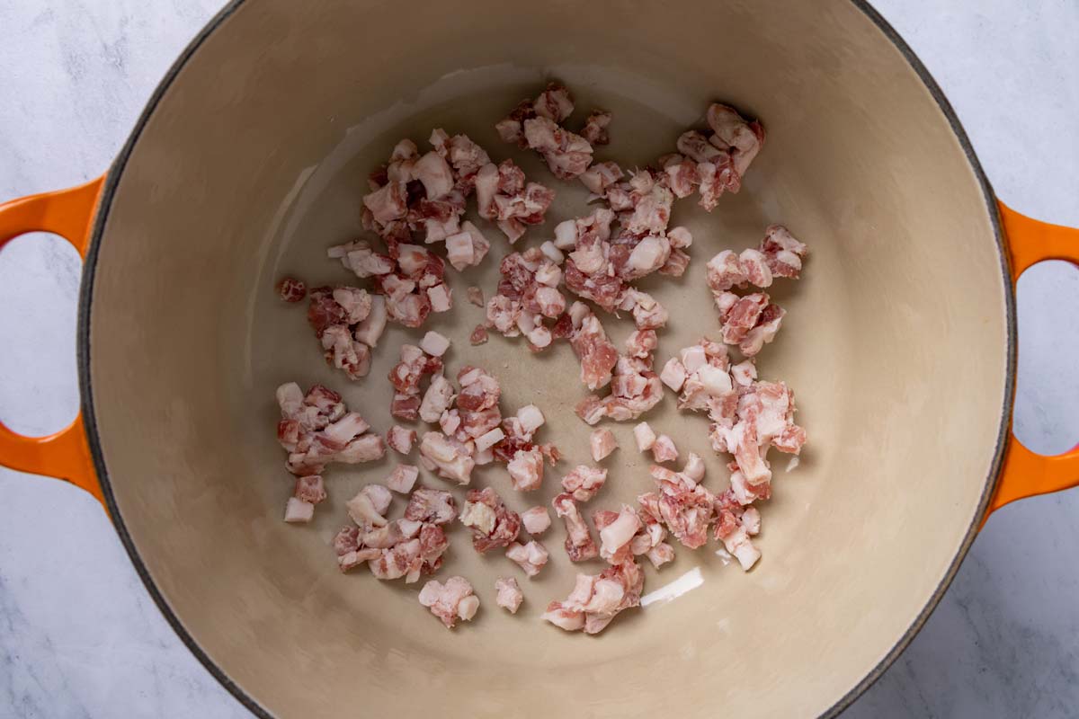 Diced pancetta added to a Dutch oven.