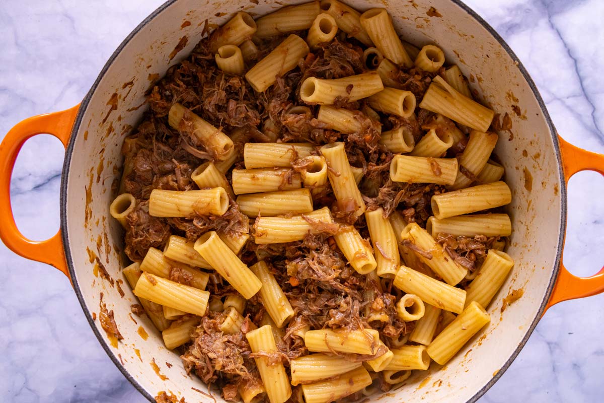 Cooked rigatoni combined with Genovese sauce in a Dutch oven.