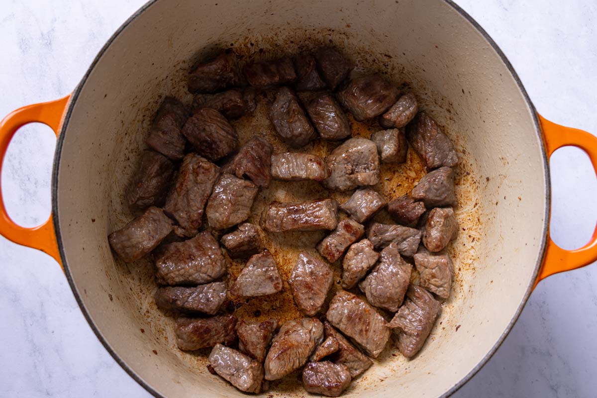 Cubes of beef seared in a Dutch oven.