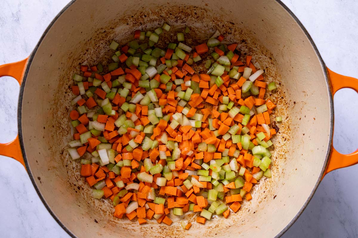 Finely chopped carrots and celery added to a Dutch oven.