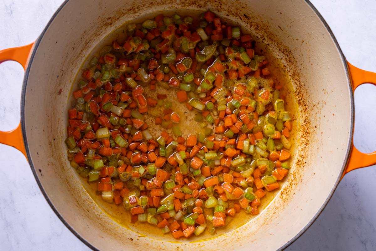 White wine added to sauteed diced carrots and celery in a Dutch oven.