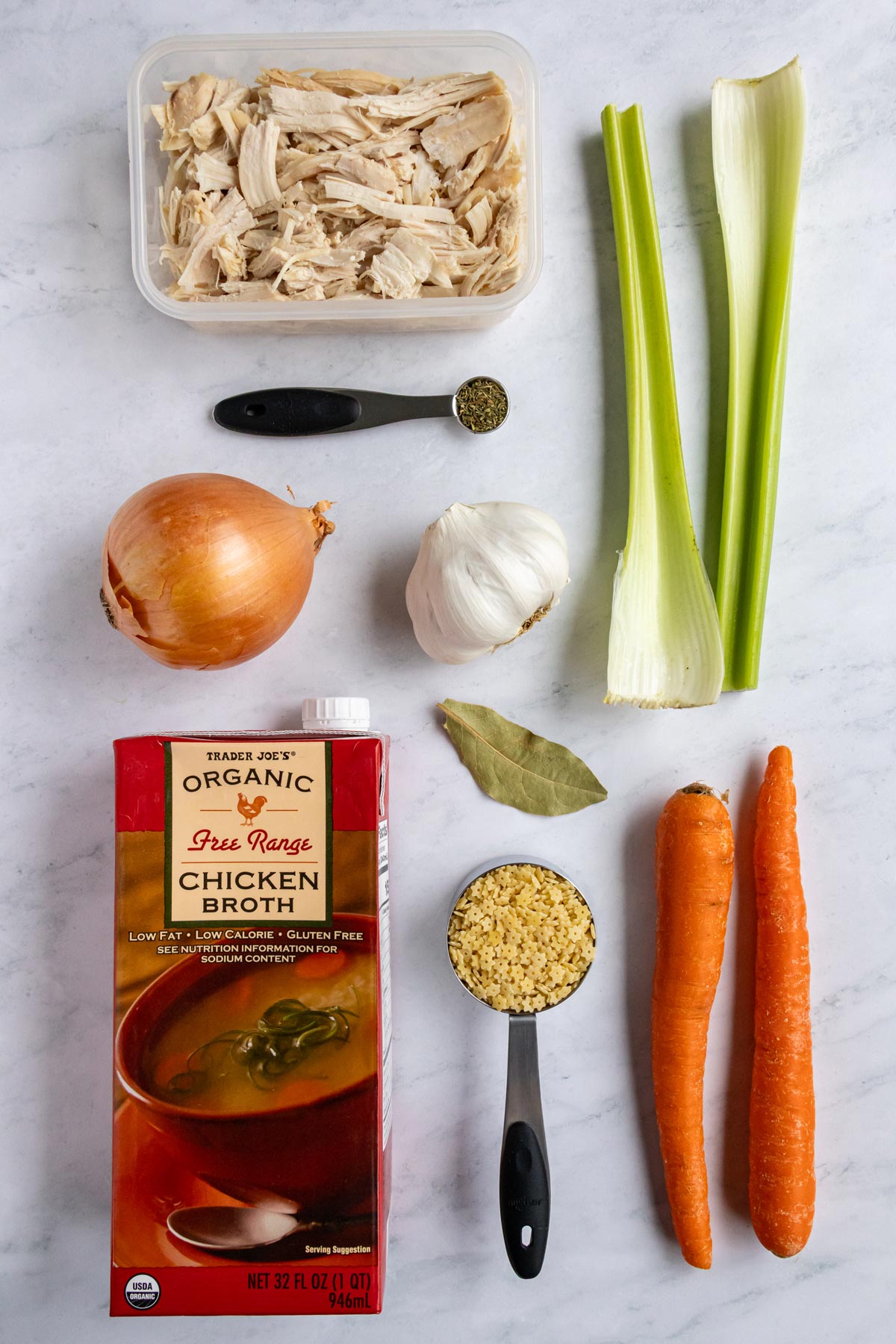 Ingredients for Italian penicillin soup on a white marble background.
