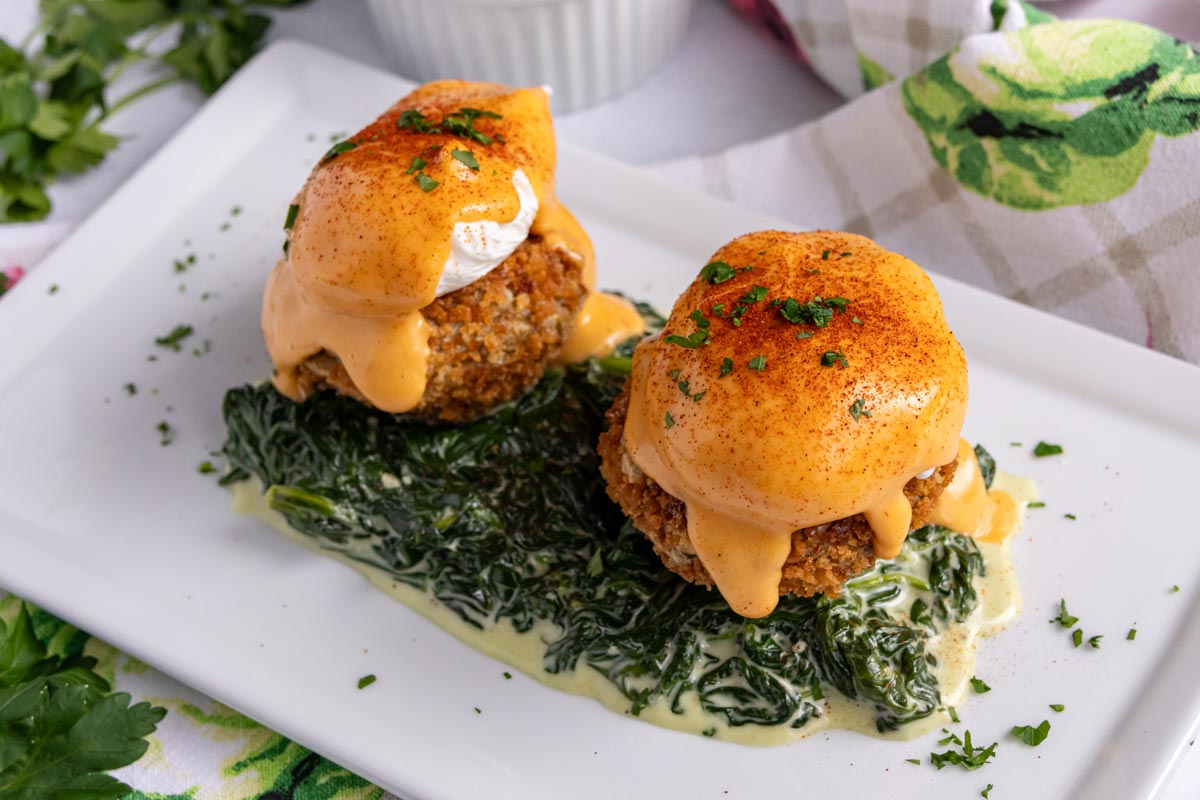 A serving of Eggs Sardou on a white rectangular plate.