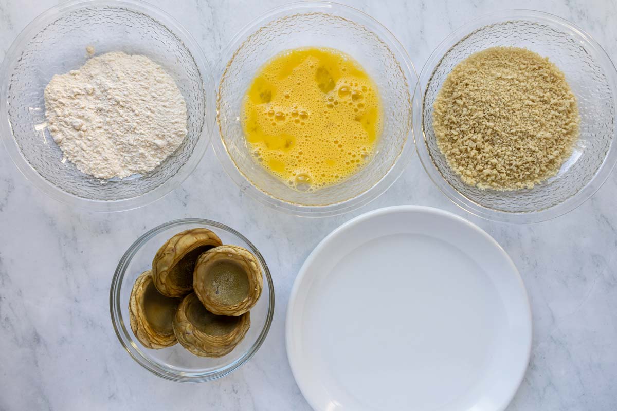 A breading station set up for breading artichoke bottoms with flour, beaten egg, and panko.