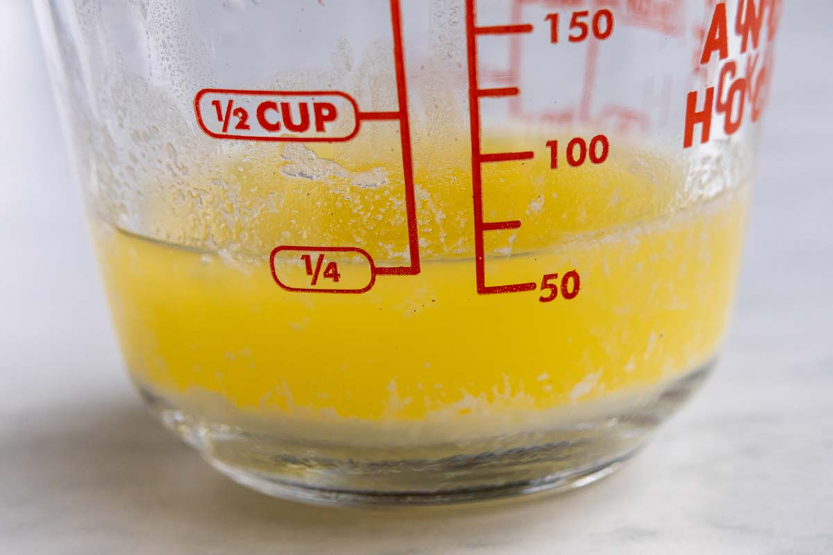 Melted butter in a glass pitcher with the milky portion settled to the bottom.