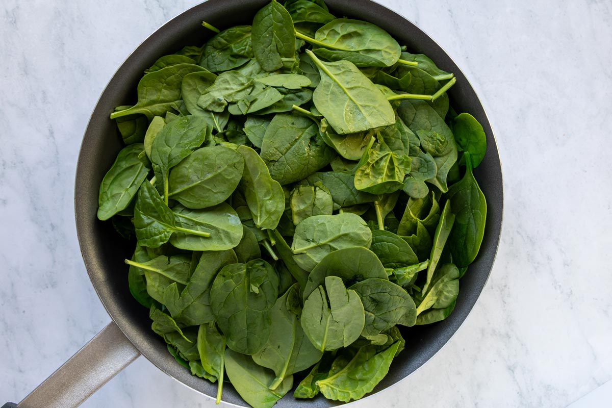 Baby spinach leaves added to a nonstick skillet.