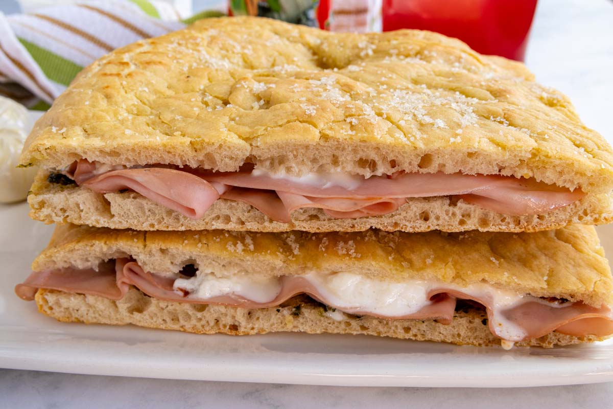 Two mortadella sandwiches stacked on top of each other.