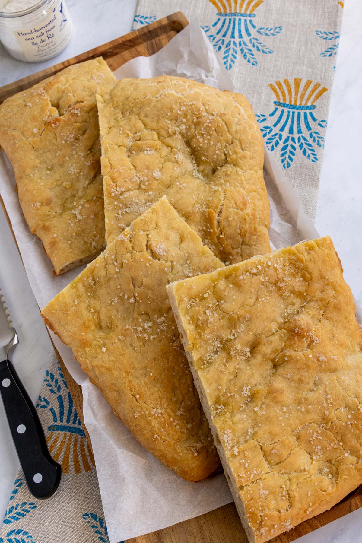 Four rectangular pieces of pizza bianca topped with flaky sea salt on a platter.