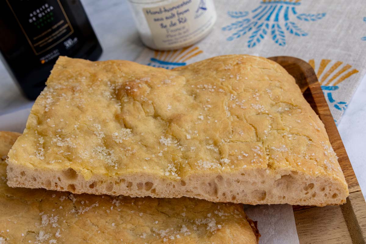 Cross-section of a piece of pizza bianca showing off its crisp golden crust and large airy holes.