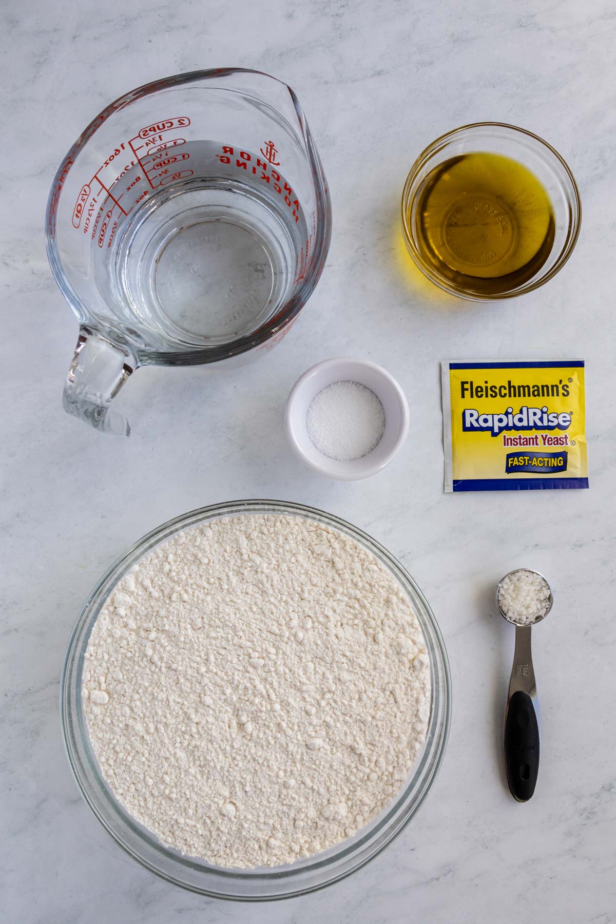 Ingredients for pizza bianca on a white marble background.