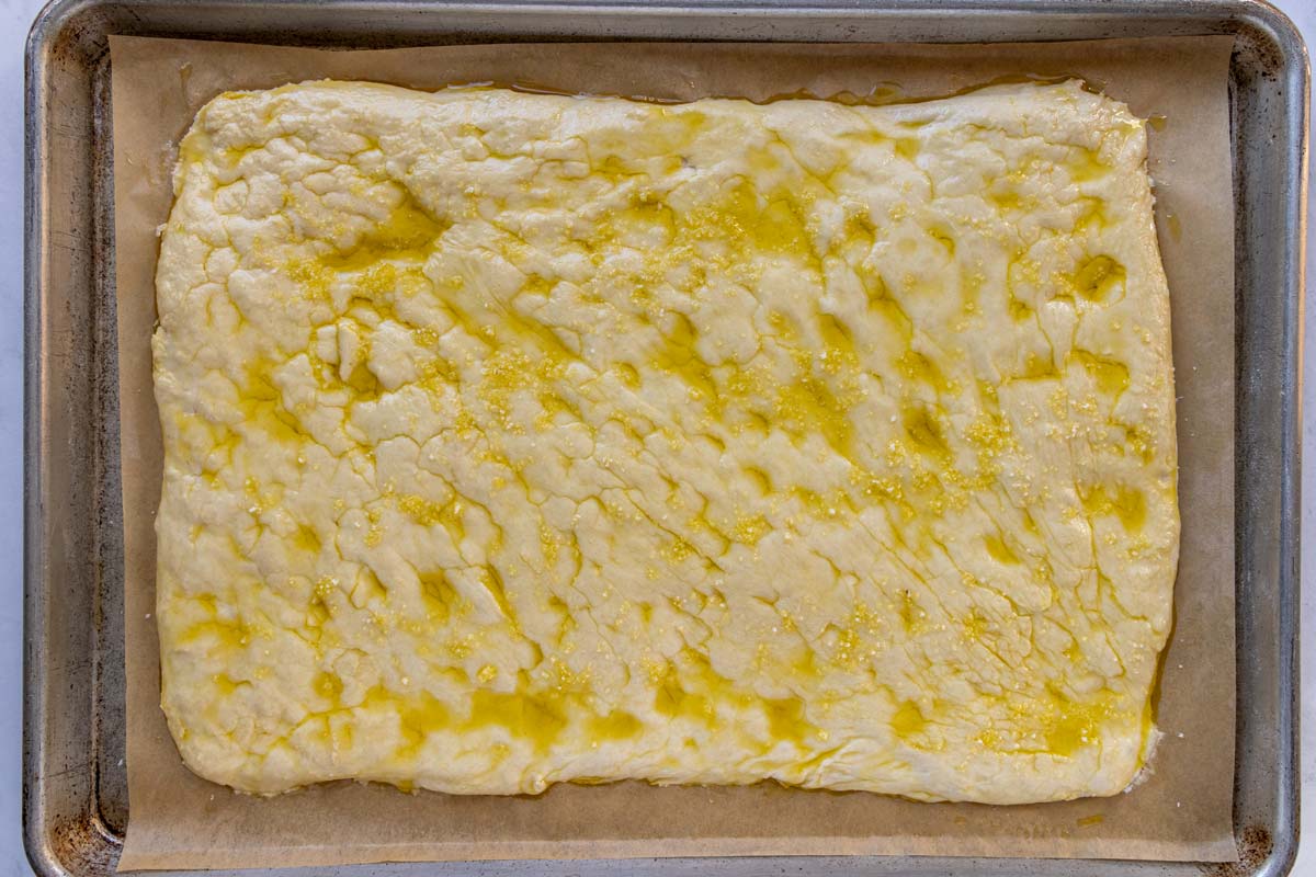 A rectangle of dough topped with olive oil and flaky sea salt.