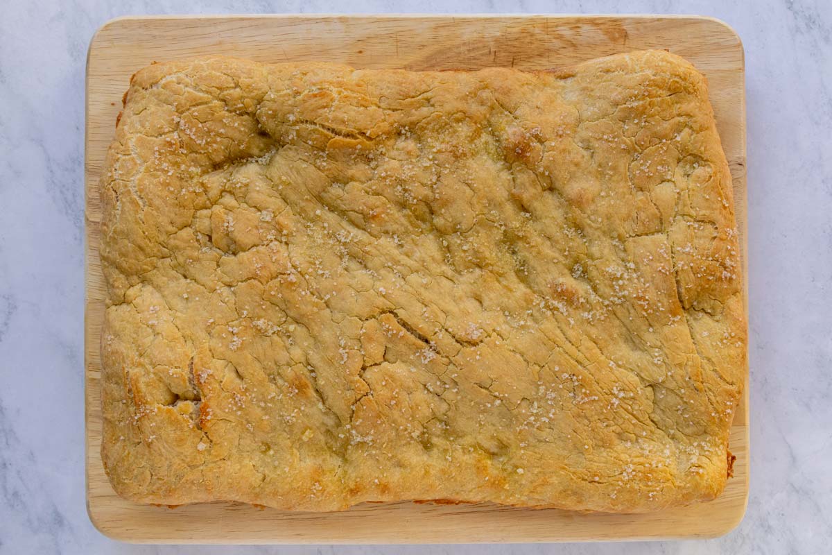 A rectangular crispy pizza bianca on a wooden board.