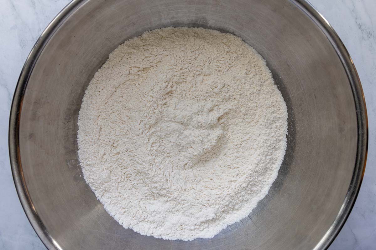 Flour, salt, and instant yeast whisked together in a metal mixing bowl.