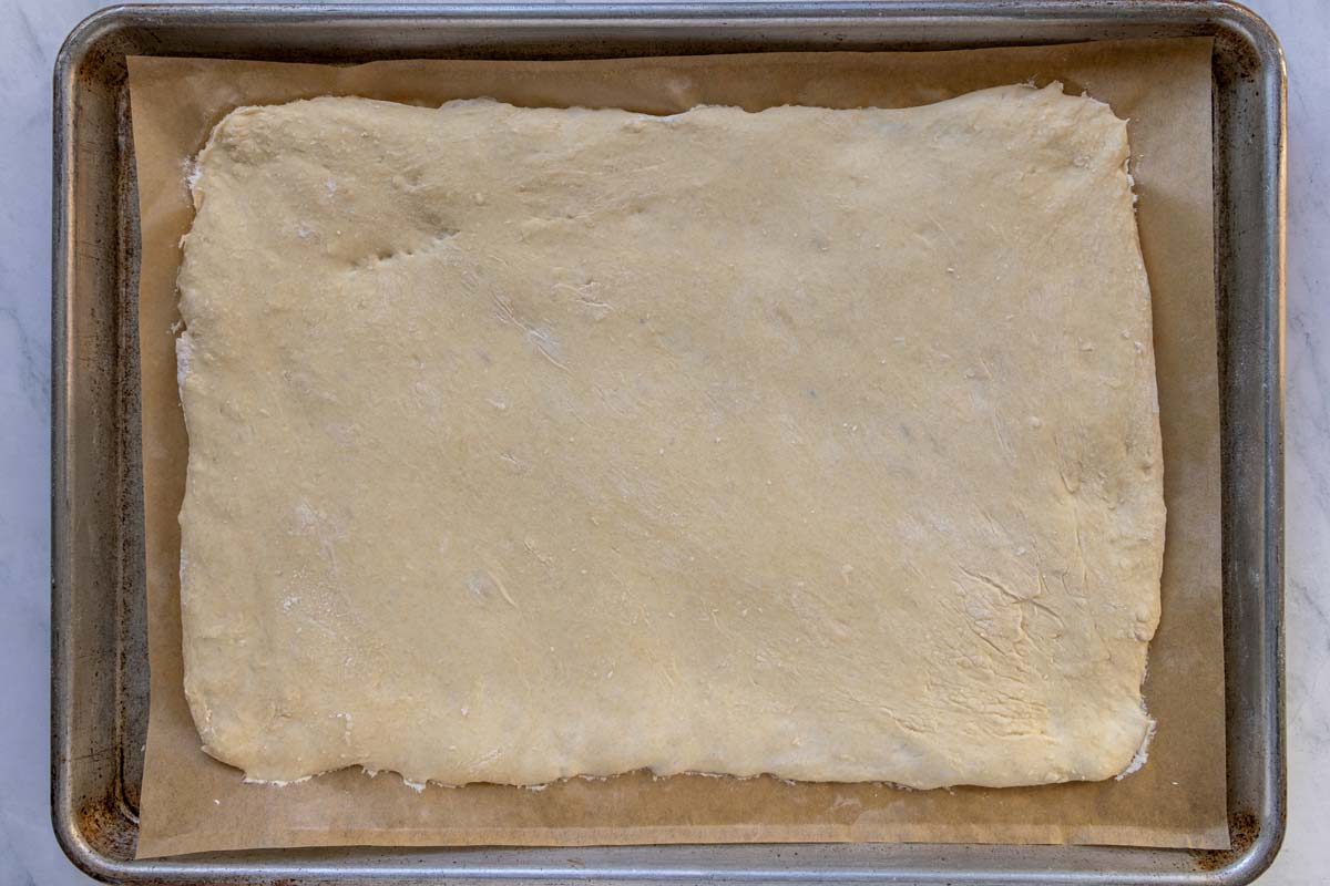 A rectangle of dough on a baking sheet after rising for 1 hour.