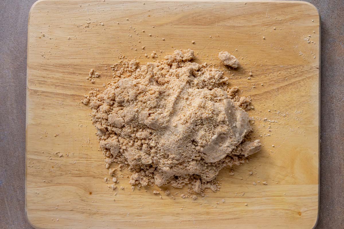 A somewhat crumbly dough on a wooden surface.