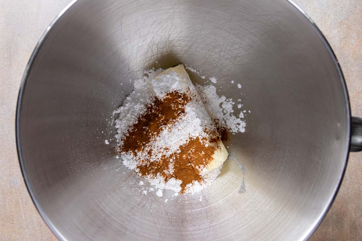 Butter, powdered sugar, and ground cinnamon in a mixing bowl.