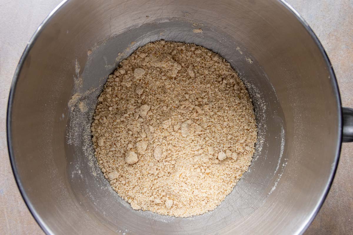 A crumbly sandy mixture in a metal mixing bowl.