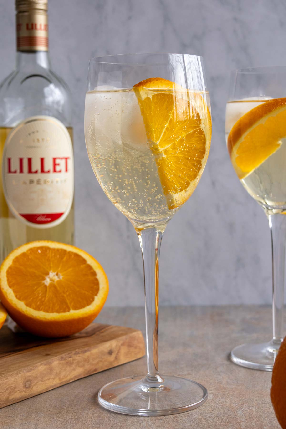A glass of Lillet Spritz garnished with a half slice of orange.
