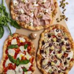 Three pinse with various toppings including a mortazza, margherita, and capricciosa pinsa.
