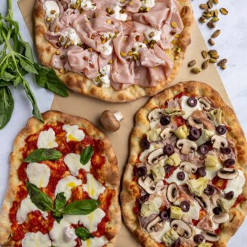 Three pinse with various toppings including a mortazza, margherita, and capricciosa pinsa.