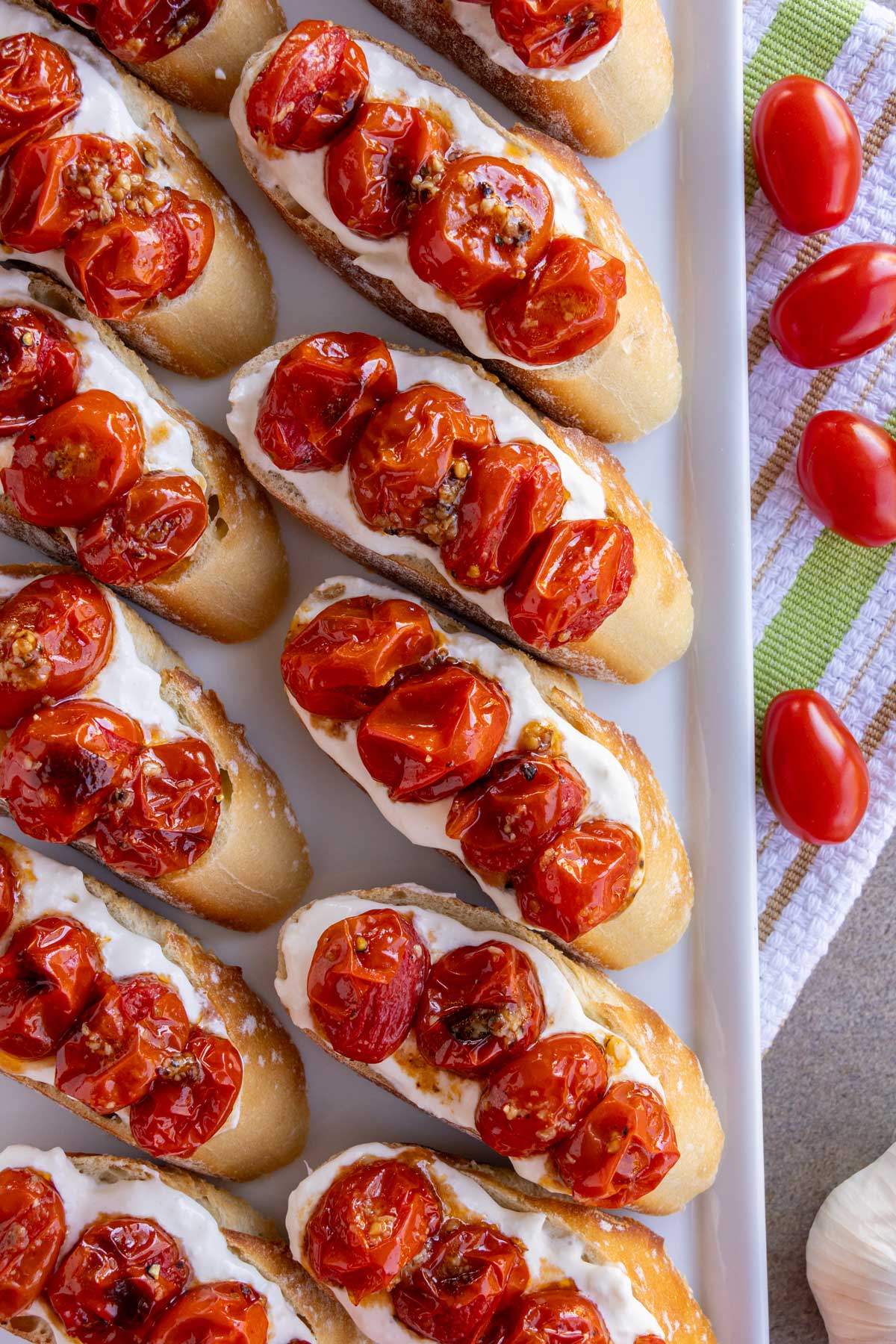 Toasted baguette slices topped with stracciatella cheese and roasted cherry tomatoes.