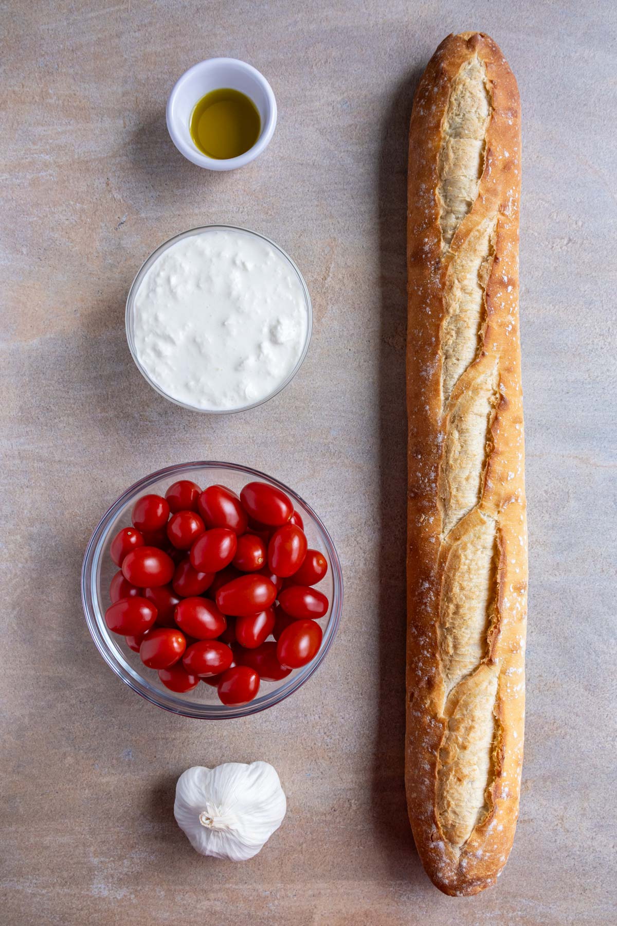 Ingredients for stracciatella bruschetta with roasted cherry tomatoes on a beige background.