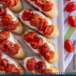 Stracciatella bruschetta with roasted cherry tomatoes arranged in rows on a platter.