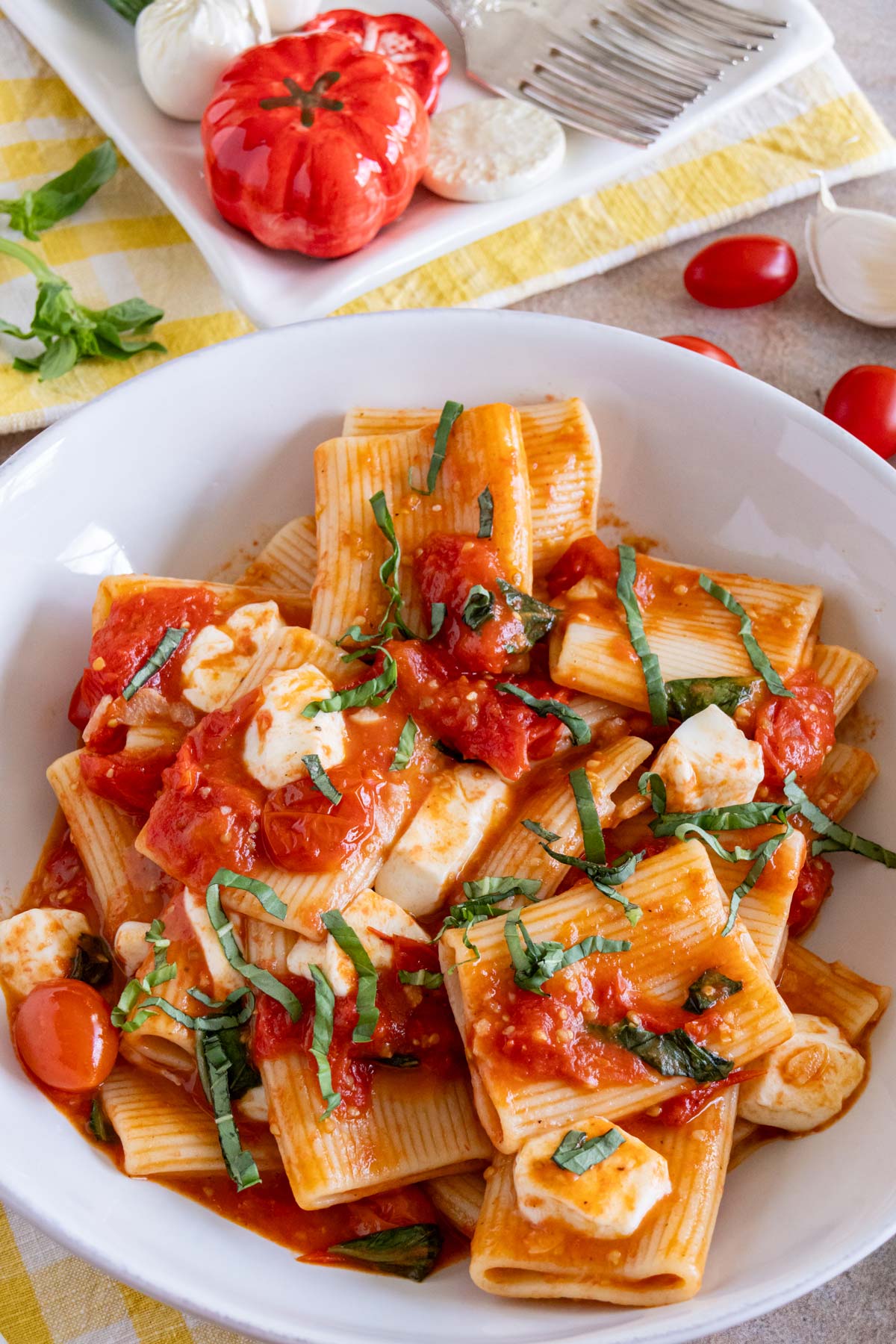 A bowl of pasta alla sorrentina made with paccheri pasta, cherry tomatoes, basil and mozzarella.