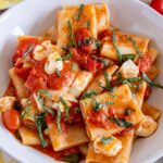 A bowl of pasta alla sorrentina made with paccheri pasta, cherry tomatoes, basil and mozzarella.