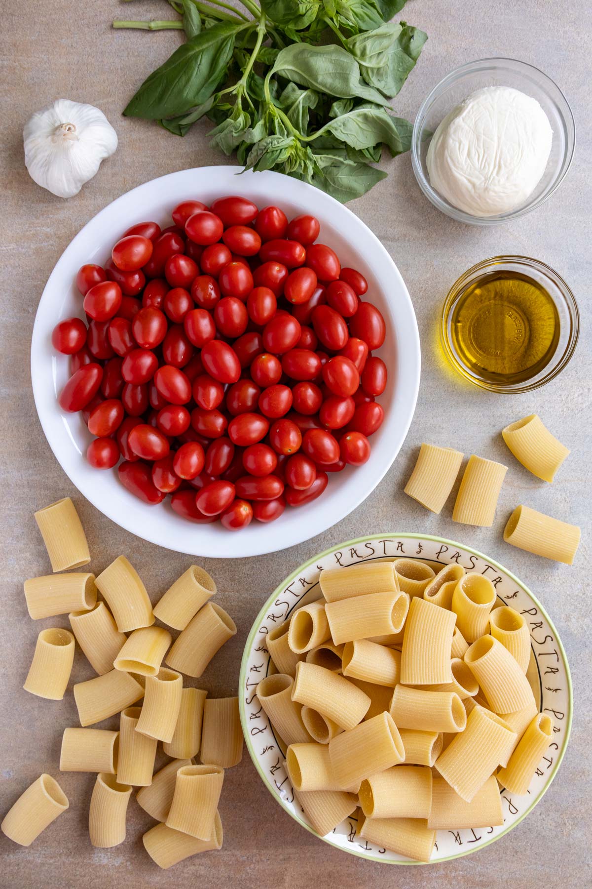 Ingredients for pasta alla sorrentina on a beige background.