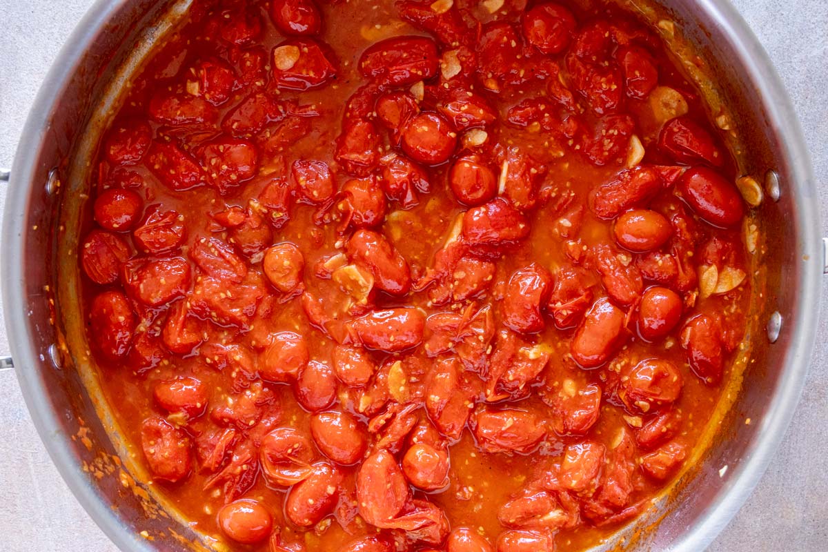 A combination of whole and smashed grape tomatoes after simmering in a skillet with garlic and olive oil.