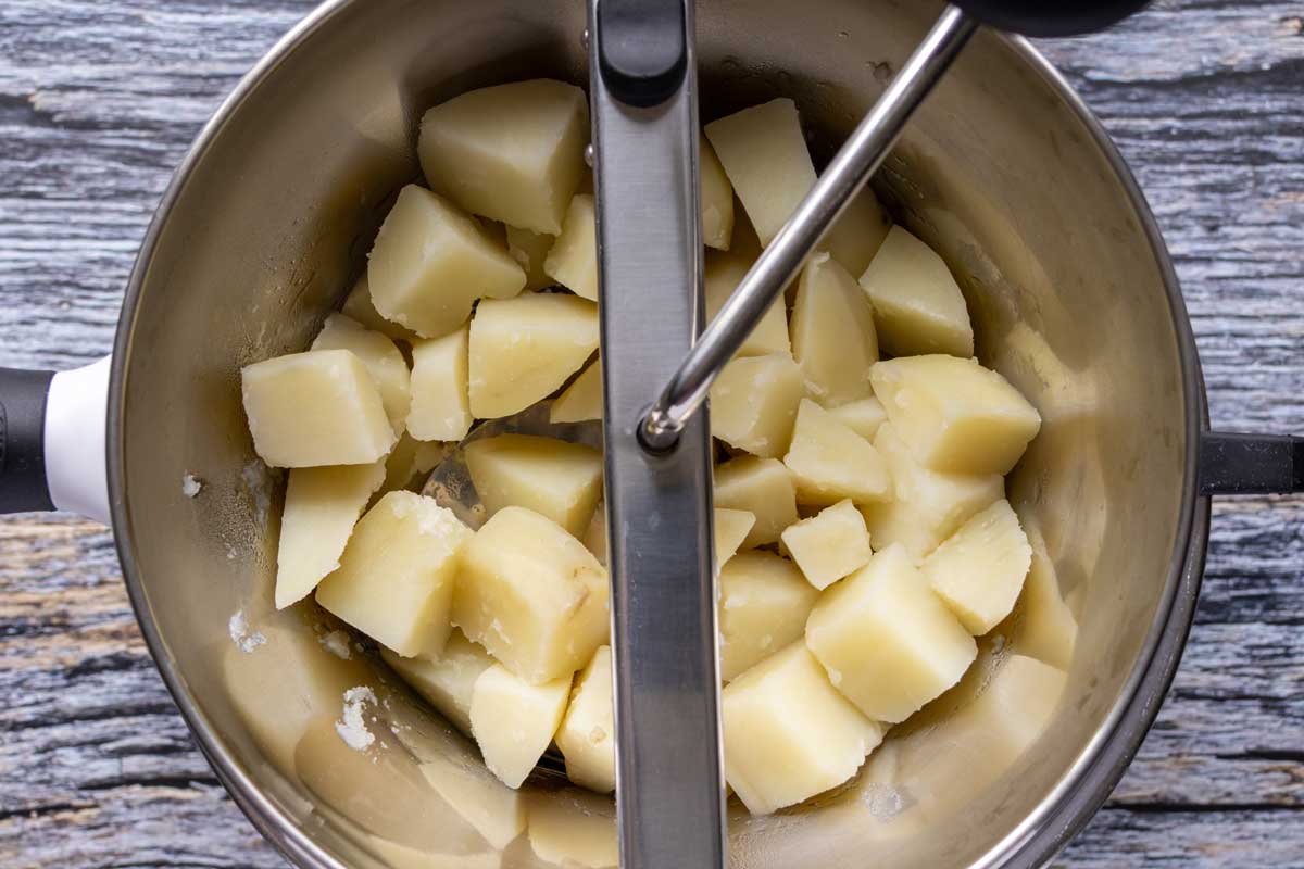 Processing cubed boiled potatoes through a food mill.