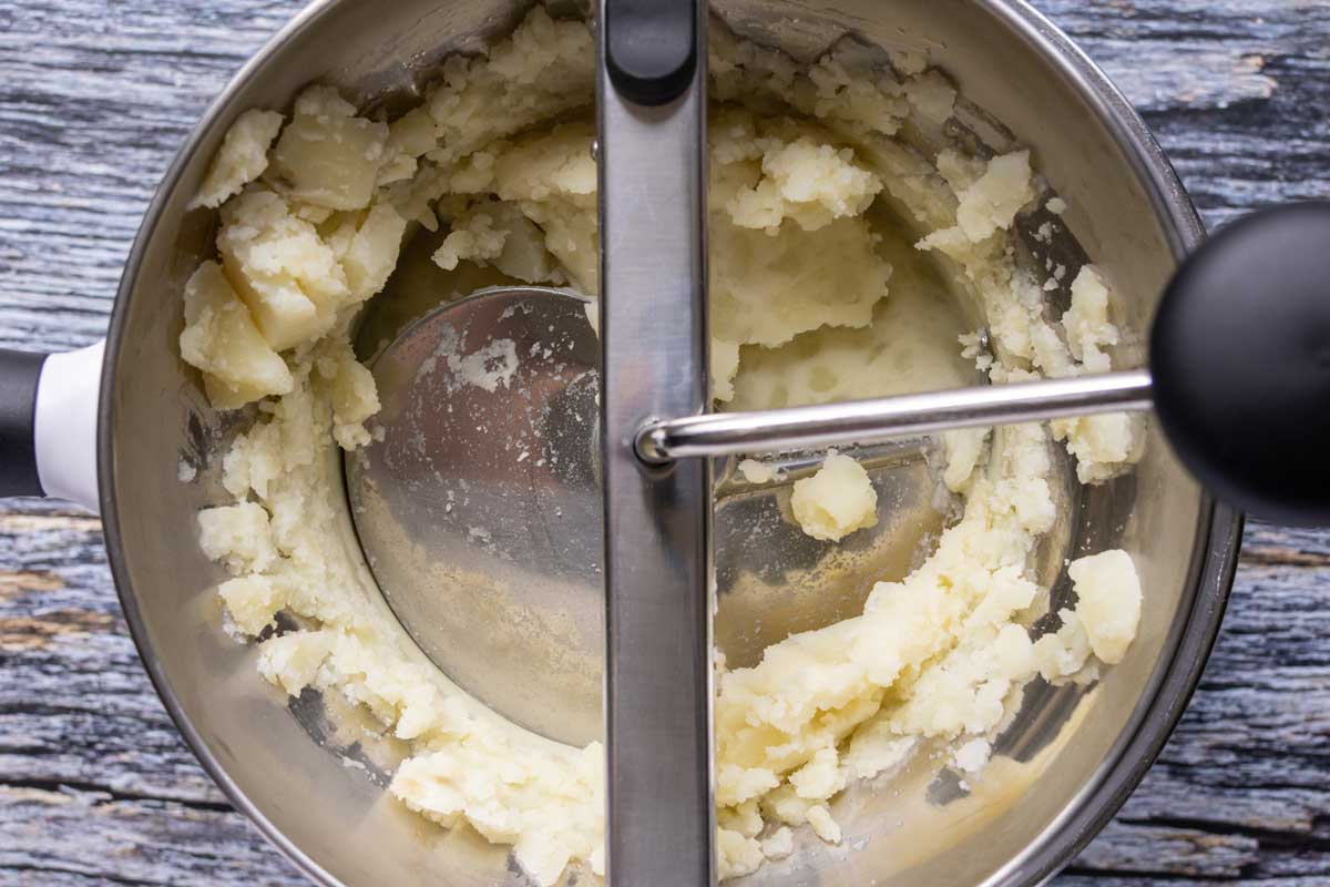 Processing boiled potatoes through a food mill.