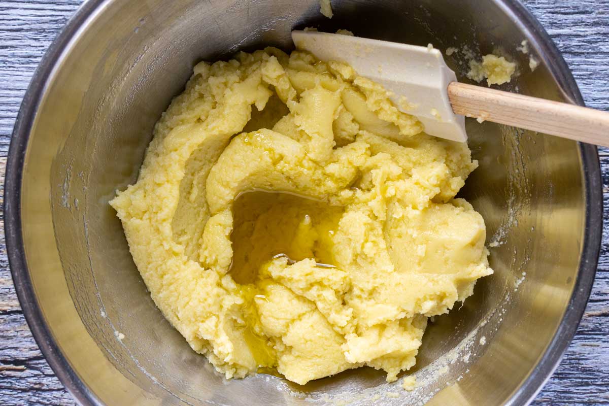 Continuing the process of stirring in extra-virgin olive oil into mashed potatoes to make skordalia.