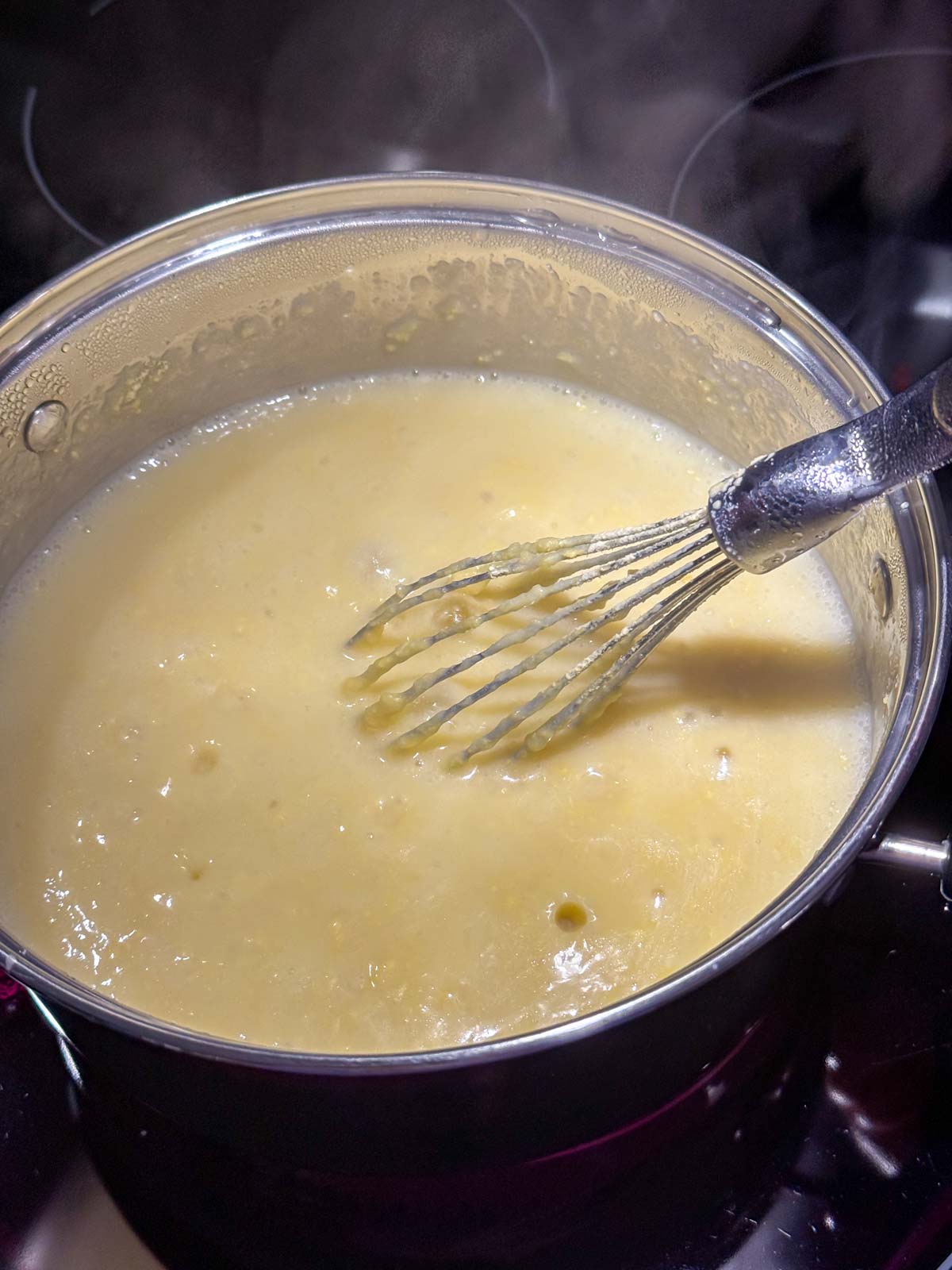 Whisking chickpea flour into simmering water on the stovetop.