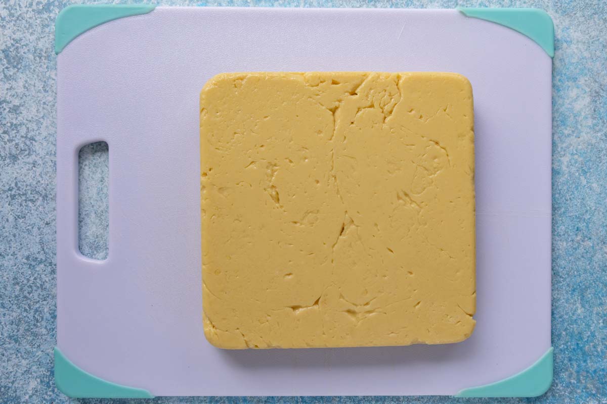 A firm square of panisse mixture flipped out onto a cutting board.