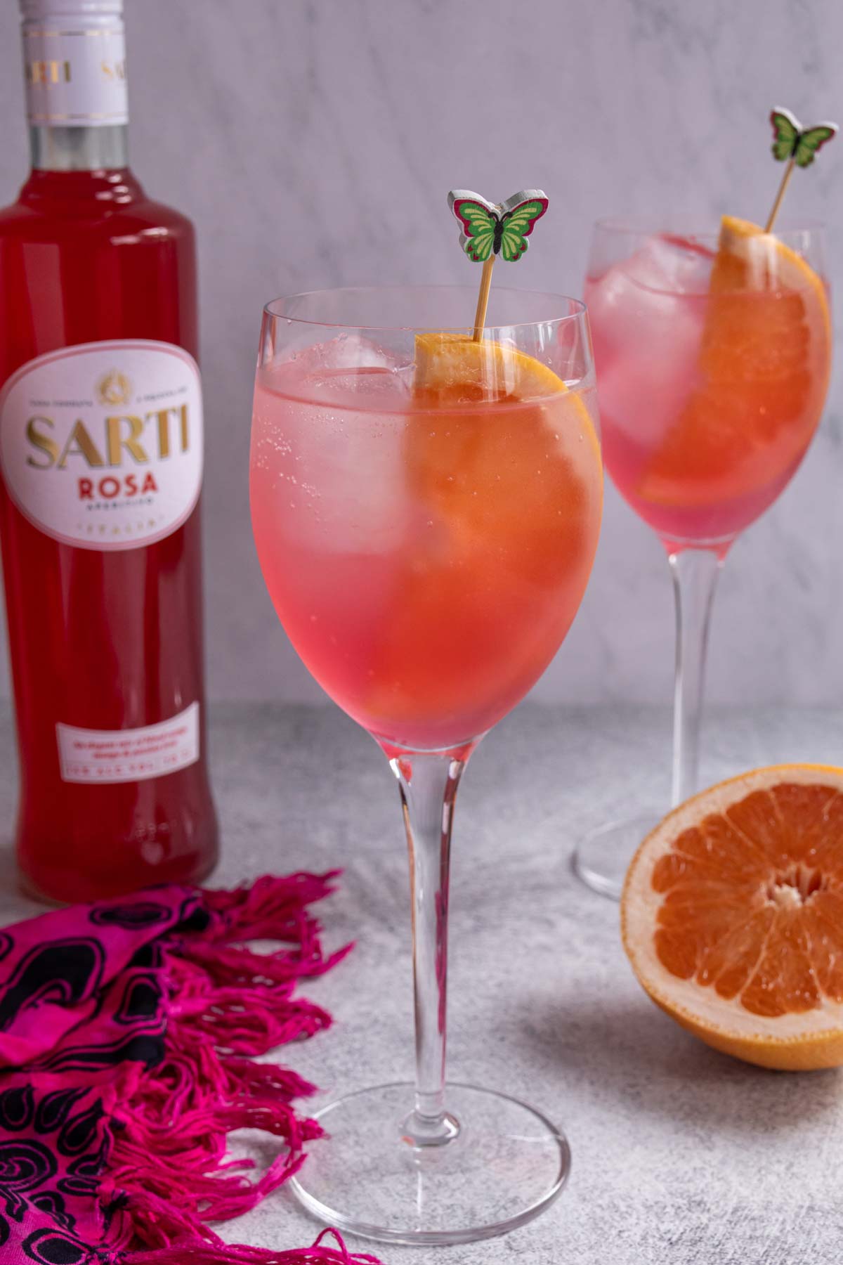 Two glasses of Sarti Spritz and a bottle of Sarti Rosa.