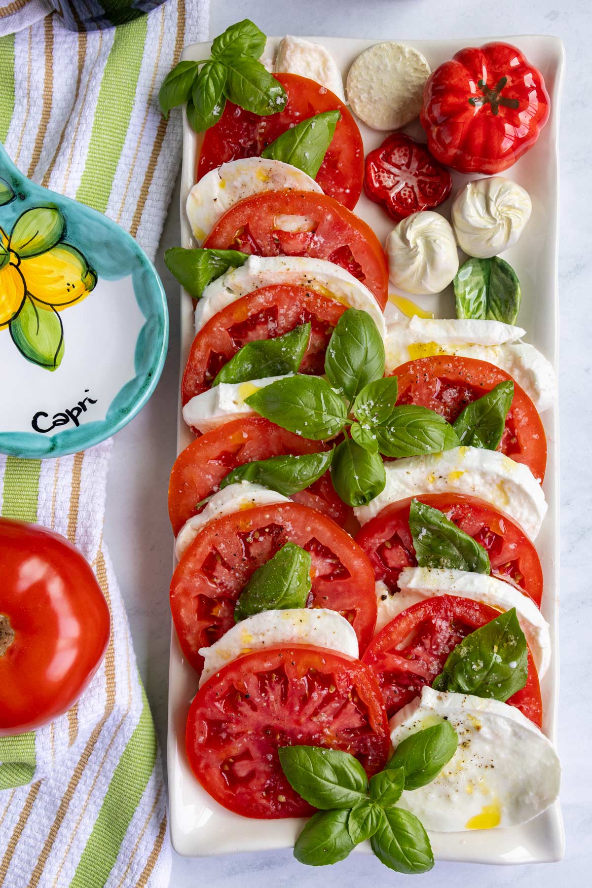 A platter of authentic caprese salad made with sliced tomatoes, buffalo mozzarella and basil.
